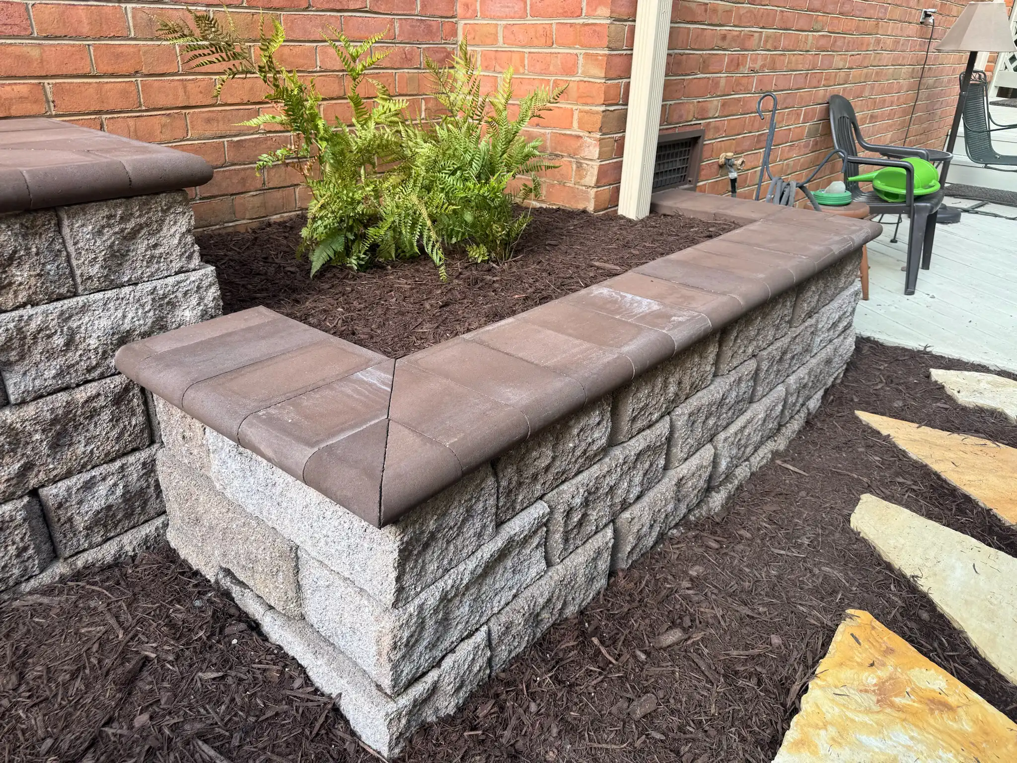 Finished retaining wall with coping stones and clean grading