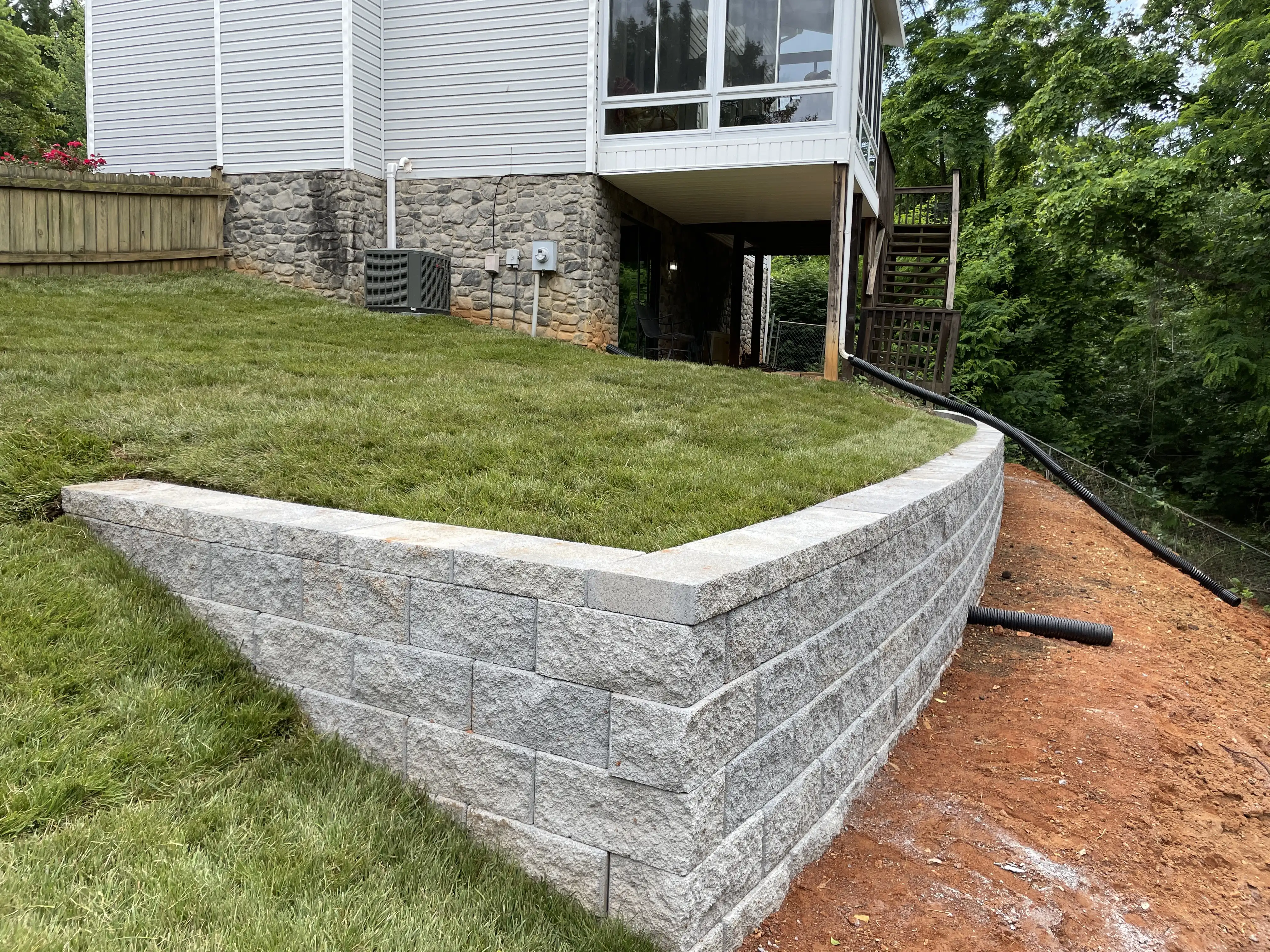 Completed segmental retaining wall with fresh sod and drainage